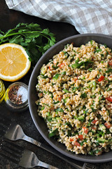 Arabic salad tabbouleh in a bowl. Middle Eastern cuisine. Healthy salad with bulgur, parsley and vegetables. Vegan salad with bulgur. Tabouli salad