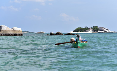 A fisherman paddles his boat out to sea, Tanjung Binga Beach, Belitung Island, Indonesia