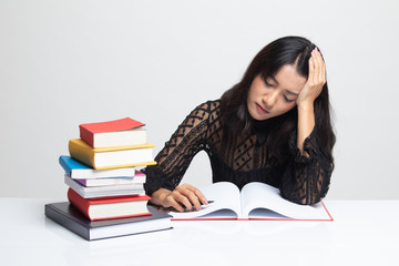 Exhausted Young Asian woman read a book with books on table.