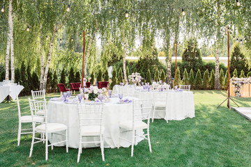 Amazing outdoor wedding table decoration with white and purple flowers on white table. Outdoor wedding