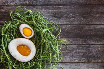 Easter handmade cookies eggs in nest on wooden background.