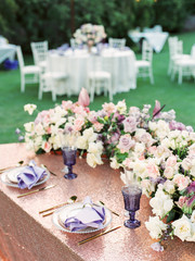 Amazing outdoor wedding table decoration with white and purple flowers on white table. Outdoor wedding