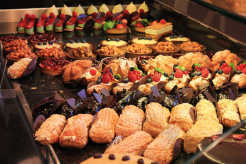 Desserts and sweets at bakery showcase. Variety of baked fresh cakes, eclair, cheesecakes and pies, tasty desserts and pastry assortment close up view in cafe window