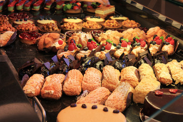 Desserts and sweets at bakery showcase. Variety of baked fresh cakes, eclair, cheesecakes and pies, tasty desserts and pastry assortment close up view in cafe window