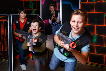 Fototapeta na wymiar Portrait of preteen boy with laser gun having fun on dark lasertag arena