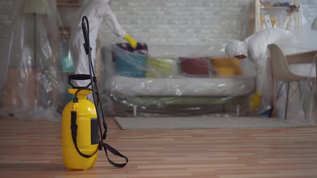 workers in protective suits shielding cellophane wrap furniture