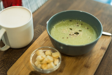 vegetarian green broccoli soup on wooden table. Vegan right lunch. Coffee and soup