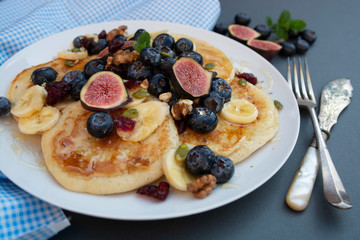 Pancakes with blueberries, mint, fruits and honey for breakfast - homemade healthy food. Breakfast idea.