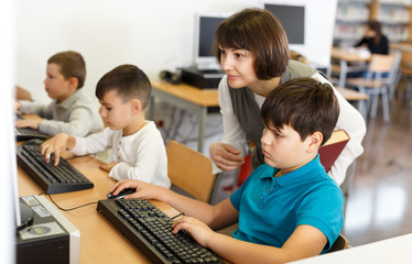Woman teacher helping boy in computer room