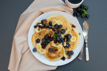 Freshmade, homemade pancakes with blueberry, dried fruits and honey. Breakfast with coffee and pancakes. Deliciious healthy food.