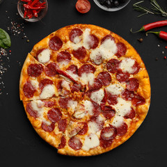 Hot pizza with salami and cheese on black background