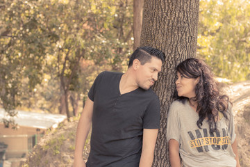 pareja jugando y coqueteando a traves de un arbol en medio del bosque, par de novios enamorados, couple playing and flirting through a tree in the middle of the forest, couple in love