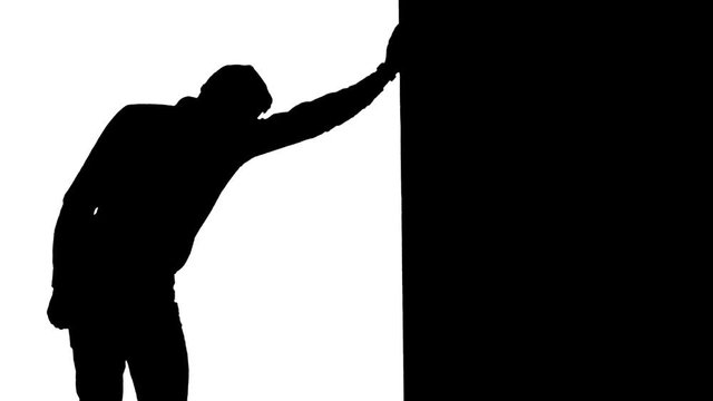 Tired guy leaned against the wall. White background. Silhouette