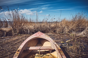 Retro toned picture of a small fishing rowboat in the reeds.