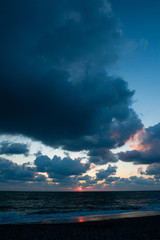 Obraz premium Sunset over sea in stormy clouds