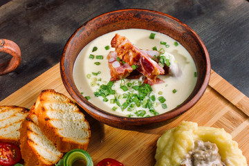 Pea soup with smoked meat in a clay plate, meat goulash with mushrooms and sauce.