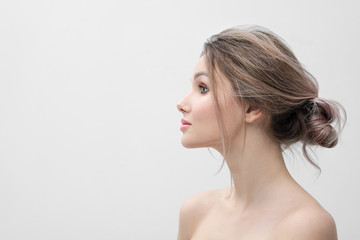 Beauty portrait of a young beautiful blonde woman, with bare shoulders in profile. Light gray background and copy space. Beautiful plump red lips.