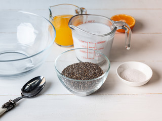 Cooking dessert ingredients with chia, milk and citrus orange on white background. Recipe steps by steps concept.