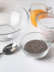 Cooking dessert ingredients with chia, milk and citrus orange on white background. Recipe steps by steps concept.