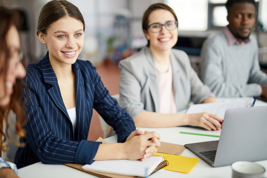 Group of contemporary people working in meeting focus on smiling young businesswoman in foreground, copy space
