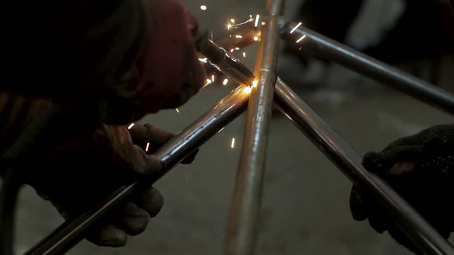 Workers in the mask are welding steel in workshop	