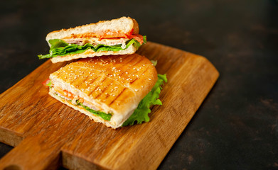sandwich on a cutting board against a background of stone