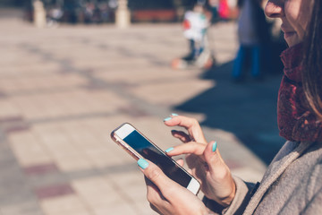 Happy girl using a smartphone in a city park. Moscow, Russia.
