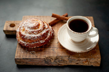 coffee with a bun on a cutting board on a background of stone, morning breakfast