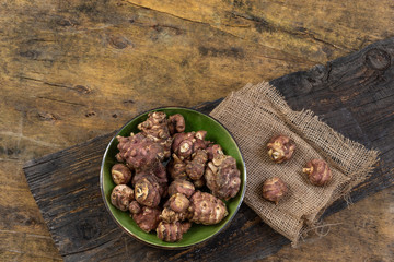 Jerusalem artichoke on green plate wooden background.