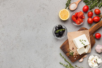 Block of feta cheese and vegetables on concrete background