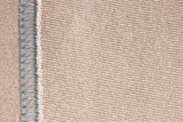 Empty beige knitted fabric with decorative elements. Knit texture with stitching. Light background for wallpaper and other elements of your design.