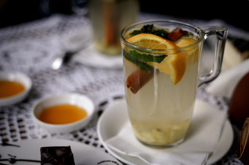 Transparent cup of tea with cinnamon, mint, orange on the table with a honey. warming fruit and mint tea in a restaurant