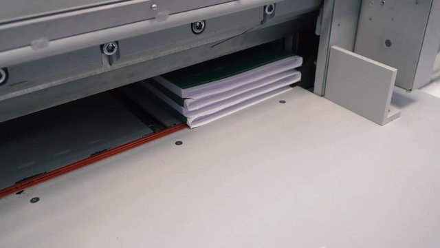 Printing house worker operating cutting machine. Worker cutting a stack of paper in a typography. Paper cutting industrial machine. Print house.