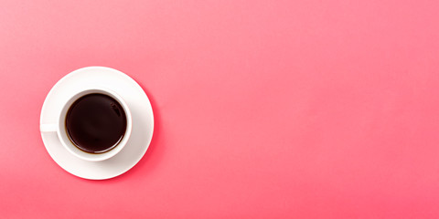 A coffee cup on a pink paper background