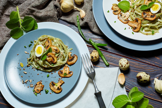 Green spinach pasta with vegetables mushrooms wheat tost and quail eggs on concrete texture background