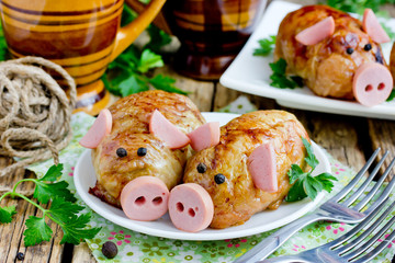 Pork meatballs - baked cutlet meatball meatloaf stuffed with minced meat and rice in crispy chicken skin shaped funny pigs with sausage snout and ears and black pepper eyes