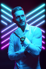Young handsome model posing in a studio in a trendy neon light. Fashionable man in a stylish suit. Vibrant color. Bright colorful light effects. Disco style. Overlay. Gel filter. Supersaturated
