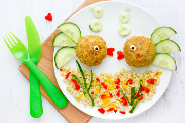 Fish meatballs with porridge and vegetable slices for funny and healthy dinner for kids, food art composition