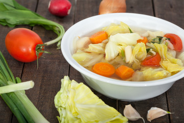 Fresh vegetablle soup in white bowl. Healthy food. Wooden background.
