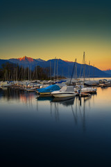 Dark green and yellow sunset with boats in the port of Ascona, Switzerland