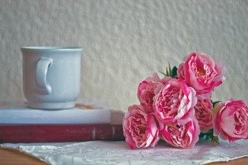 Pink peonies with a cup of coffee and some books