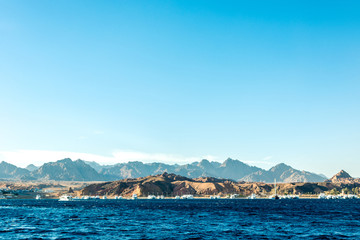 Seascape, view of the blue sea with high bald mountains in the background