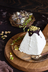 Paskha (Pasha) with pistachios decorated with chocolate glaze and pistachios. Traditional Russian orthodox Easter quark dessert. Easter food background. 