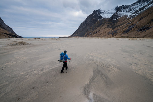 Female backpacker walks across the vast sands of Horseid beach, Moskenesøy, Lofoten Islands, Norway