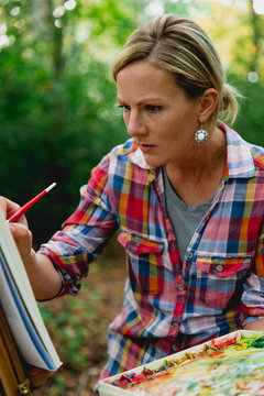 Female painter creating watercolor painting in forest, Neenah, Wisconsin, USA