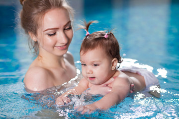 young mother bathes the baby in the pool.