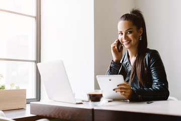 Beautiful girl working out a plan of the project and concept. Girl paints a website design on a laptop. student prints a message on the phone in the messenger. Development. Digital marketing