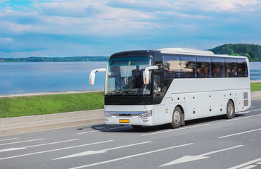 Tourist bus moves along the road along the lake shore