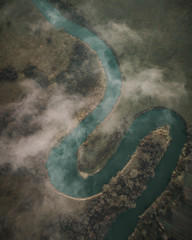 Upstair view at curly river at sunrise in cloudy weather with clouds above the river.