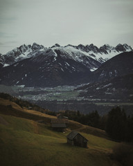 Huts on a hill in Austrian alps near Innsbruck with snowy mountains on the background.